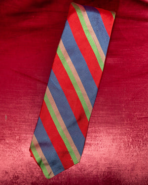 Striped tie with red, blue, and green pattern on a red fabric background