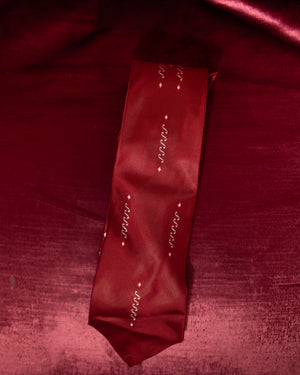 Red tie with decorative patterns on a red fabric background