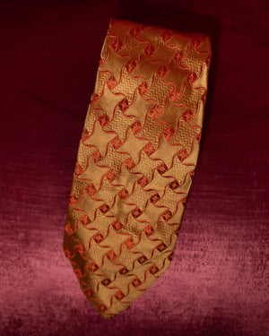 Gold tie with red pattern on a maroon background