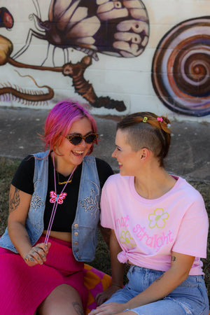Two people sitting outdoors with a colorful mural in the background