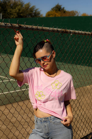 Person wearing a pink t-shirt with floral designs on a tennis court.