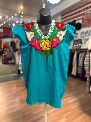 Turquoise top with colorful embroidery on a mannequin in a store setting