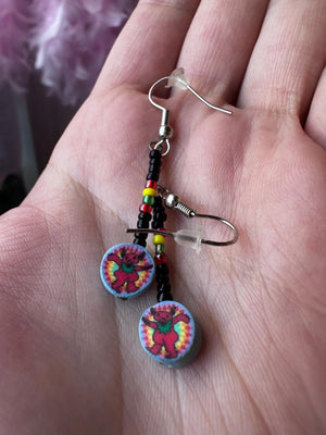 Colorful beaded earrings on a hand with a blurred background