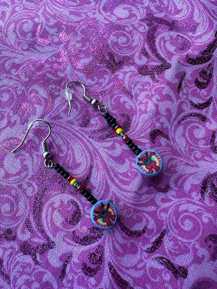 Pair of beaded earrings on a purple patterned fabric background