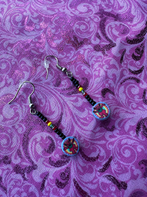 Pair of beaded earrings on a purple patterned fabric background