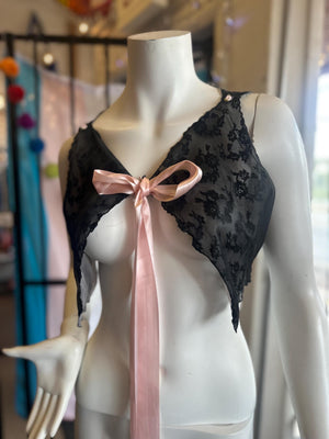 Mannequin wearing a black lace top with a pink ribbon and a white outfit.