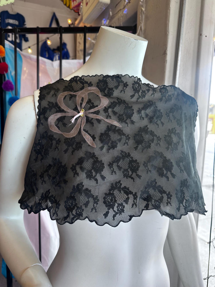 Black lace shrug on a mannequin with a blurred store background