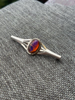 Silver ring with a colorful gemstone on a textured gray surface