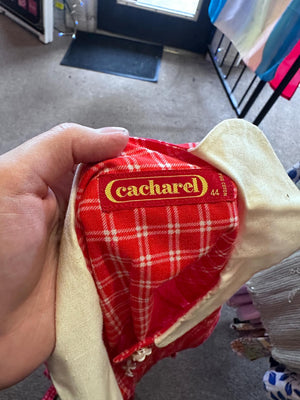 Red plaid pouch with 'Cacharel' branding held by a hand in an indoor setting.