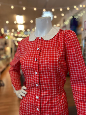 Red checkered dress on a mannequin with a blurred indoor background