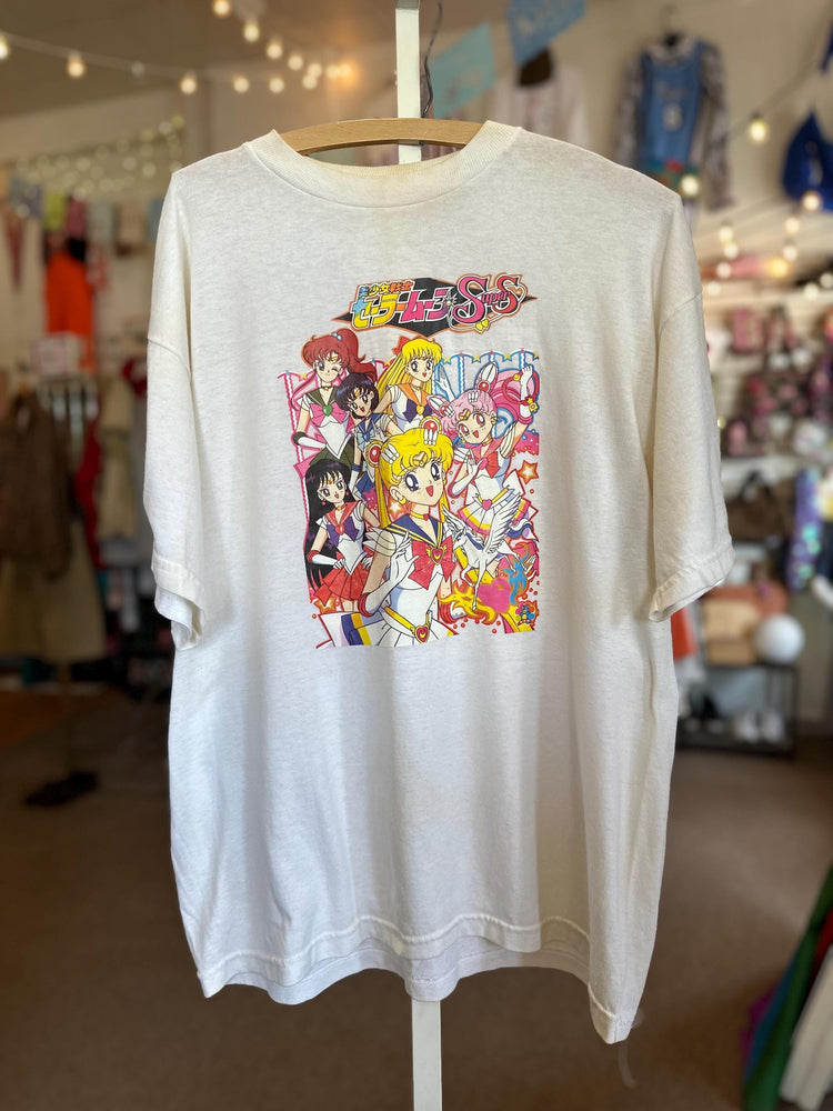 White t-shirt with colorful graphic design of animated characters on a hanger in a store.